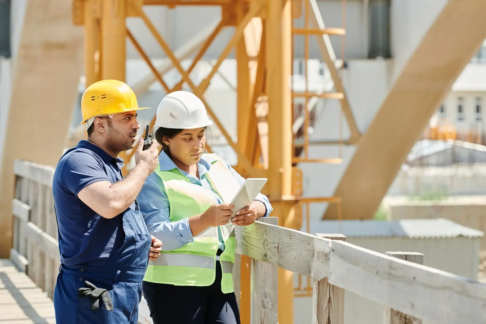 Two site engineers reviewing project information on a tablet at a construction site